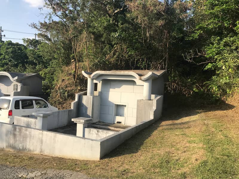 後ろに木々や草が生い茂る沖縄のお墓の草刈り後の様子